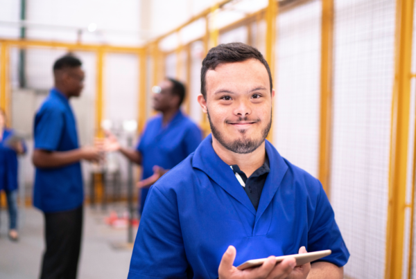 Developmentally Disabled Employee in a blue shirt and peers in an article about Developmental Disability hiring and support