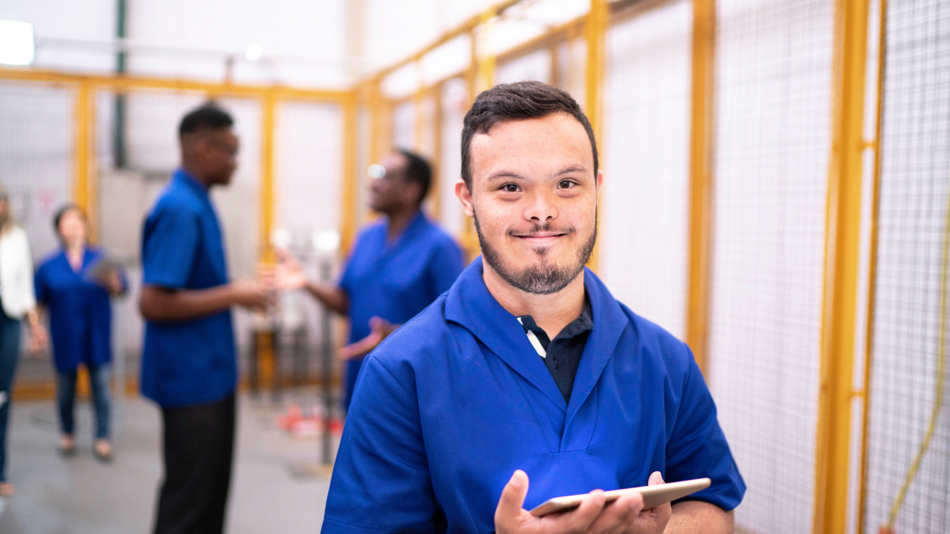 Developmentally Disabled Employee in a blue shirt and peers in an article about Developmental Disability hiring and support