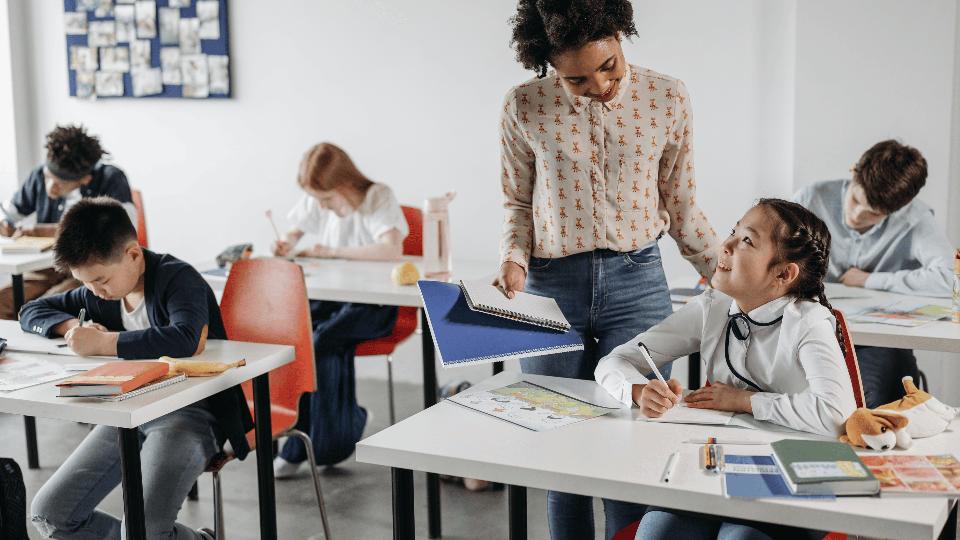 Teacher helping her students in an article about teachers getting unemployment during the summer